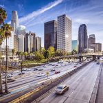 City skyline with freeway and palm trees.