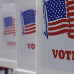 Voting booths with American flags and "VOTE" signs.