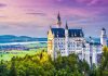 Castle surrounded by forest with scenic background.