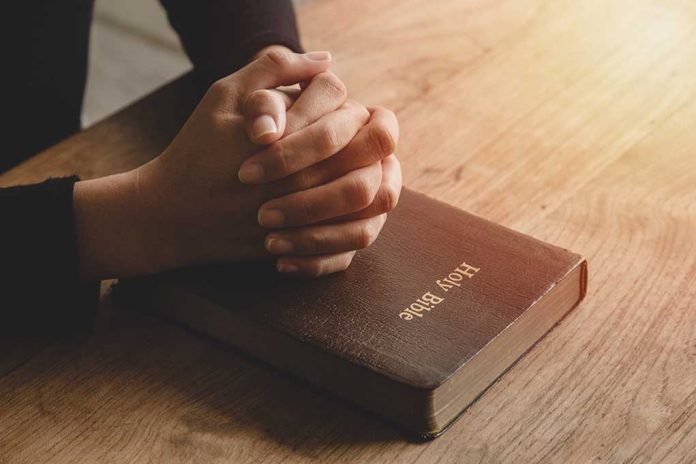 Hands praying on a Bible.