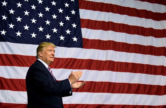 Man in front of large American flag, clapping.