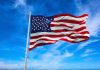 American flag waving against a blue sky.