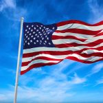 American flag waving against a blue sky.