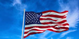 American flag waving against a blue sky.