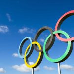 Olympic rings sculpture against blue sky.