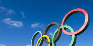 Olympic rings sculpture against blue sky.