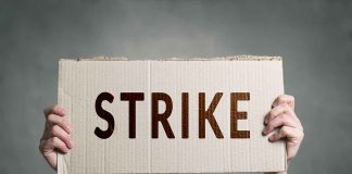 Two hands holding a cardboard sign saying "STRIKE".