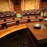 Empty courtroom with scales of justice in foreground.