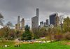 People relaxing in a park, city skyline background.