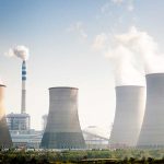 Four cooling towers of a power plant emitting steam.