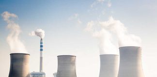 Four cooling towers of a power plant emitting steam.