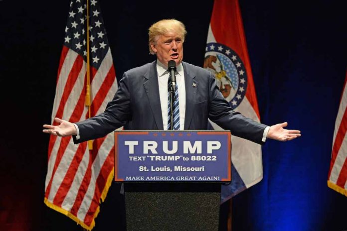 Man speaking at podium with American flags behind.