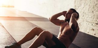 Man performing sit-ups in a gym setting.