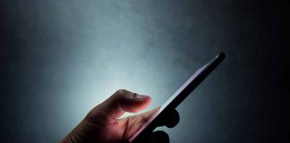 Hand holding a smartphone in the dark.