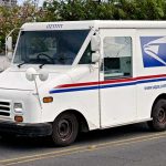 USPS mail truck driving down the street.