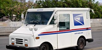 USPS mail truck driving down the street.