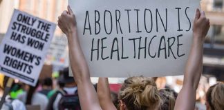 Protestors holding signs about women's rights and healthcare.