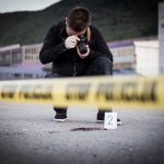 Photographer documenting crime scene with evidence marker two
