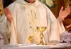 Priest in white robe with chalice and book