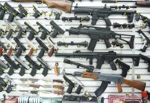 Wall display of various firearms in a store.