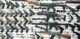 Wall display of various firearms in a store.