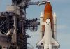 Space shuttle on launch pad with support structure.