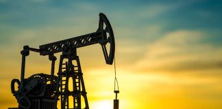 Oil pump jack silhouetted against sunset sky.