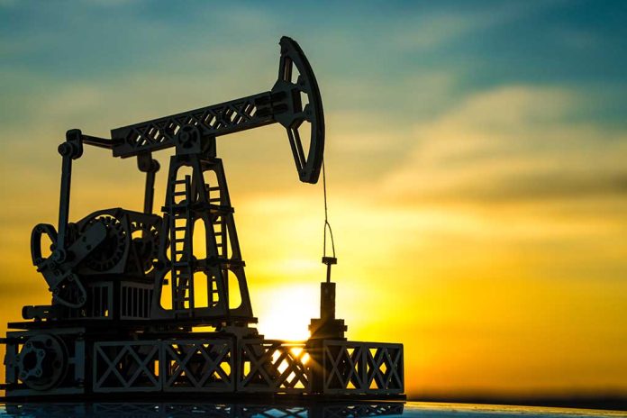 Oil pump jack silhouetted against sunset sky.