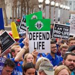 Pro-life rally with people holding various signs.