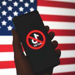 Phone displaying TikTok ban symbol in front of flag