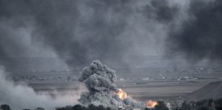 Explosion with smoke and fire in open landscape.