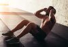 Man performing sit-ups in a gym setting.