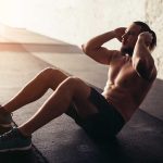 Man performing sit-ups in a gym setting.