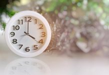 White analog clock with blurred green background