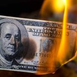 Burning hundred-dollar bill with visible flames.