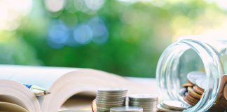 Open book pen coins jar on table