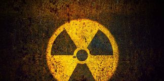 Yellow radiation warning symbol on rusty metal surface.