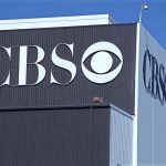 CBS logo on building exterior under blue sky.