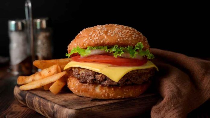 Cheeseburger with fries on a wooden board.