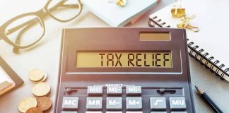 Calculator display reads "TAX RELIEF" amidst coins and glasses.