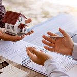 Hands exchanging house model over documents and calculator