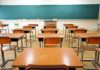 Classroom with wooden desks and empty green chalkboard.