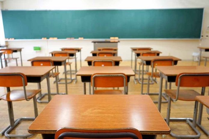 Classroom with wooden desks and empty green chalkboard.