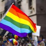 People holding and waving a rainbow flag.