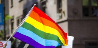 People holding and waving a rainbow flag.