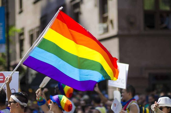 People holding and waving a rainbow flag.