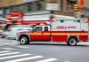 Red ambulance speeding through city intersection.