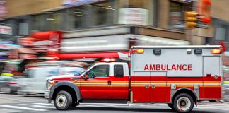 Red ambulance speeding through city intersection.