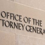 "Office of the Attorney General" sign on concrete wall.