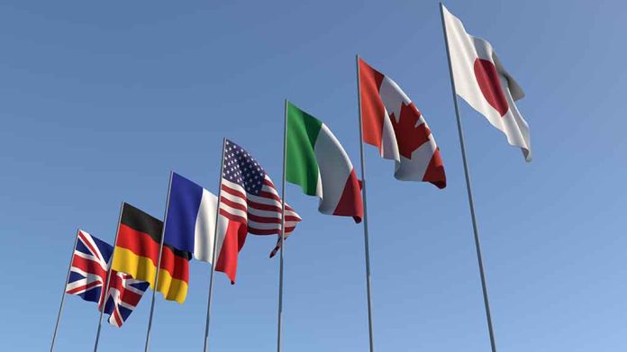 Flags of seven countries against clear blue sky.